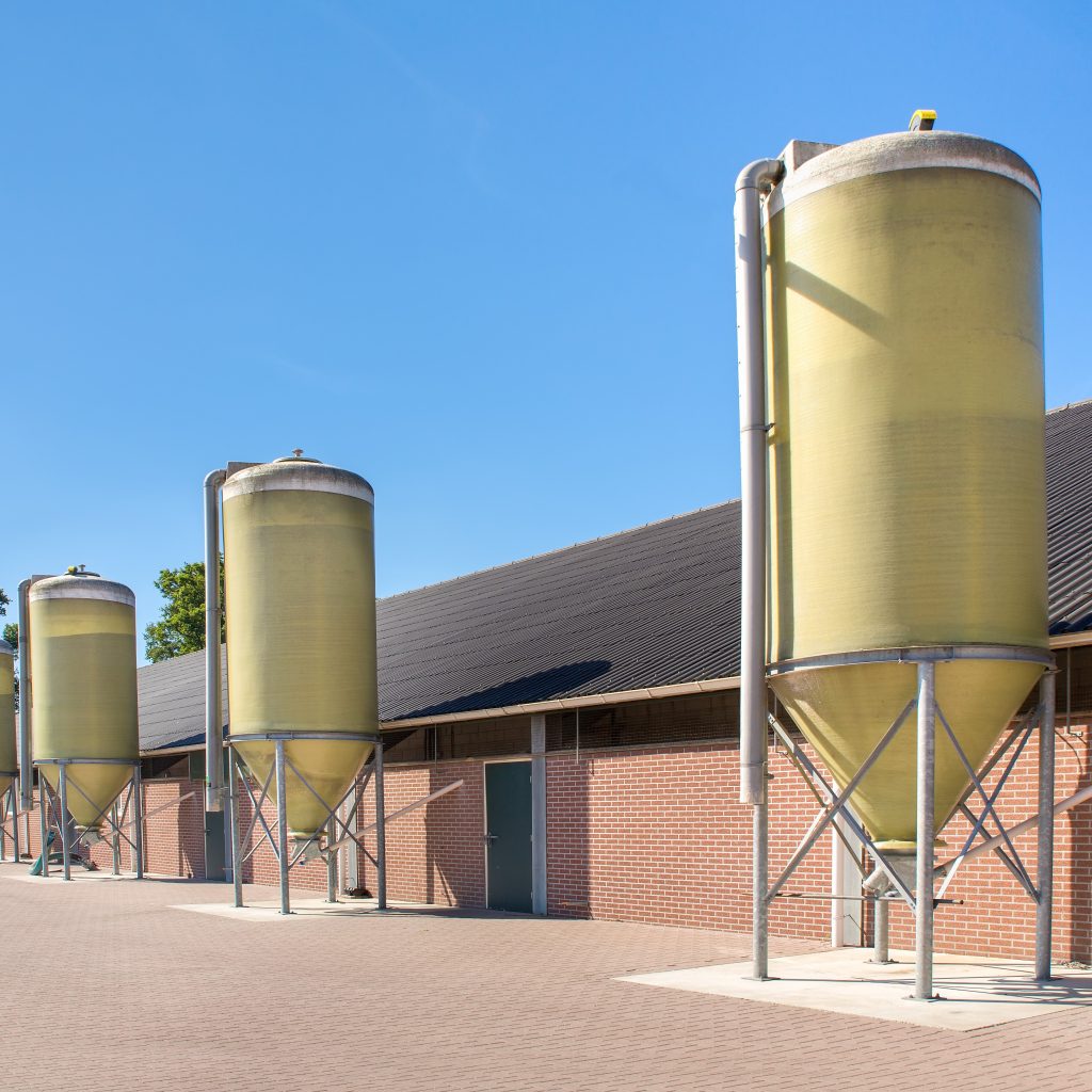 The side of an agricultural building with metal silos present as well.