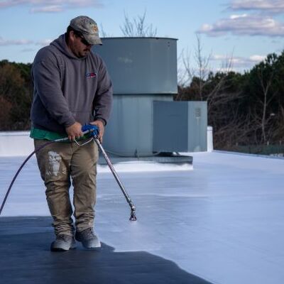 A Contractor Sprays Flat Roof Coating.